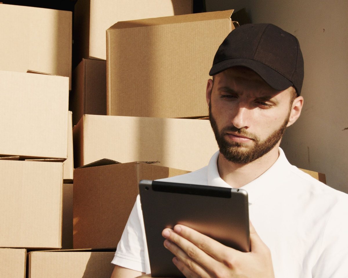 Delivery driver reviewing a shipment on a tablet beside stacked cartons in a van